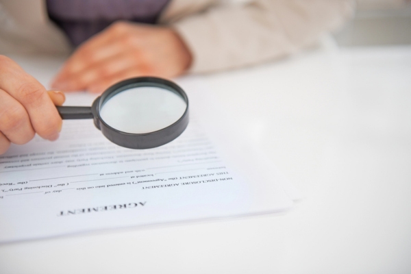 closeup on a businesswoman reviewing contract with a magnifying glass