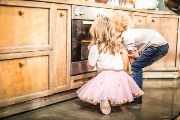 little girl and boy looking at propane powered oven while baking