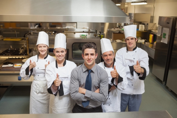 restaurant manager with 4 chefs doing a thumbs up at a restaurant kitchen