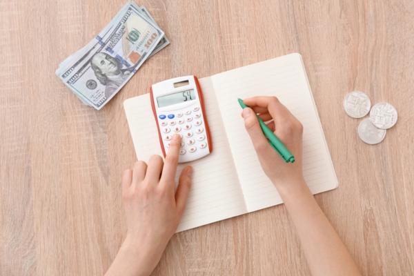 Woman with calculator and notebook determining propane usage at home