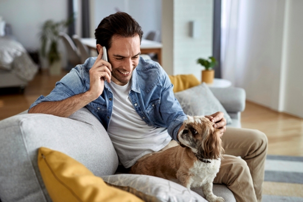 man calling for oil delivery using his mobile phone while petting his dog