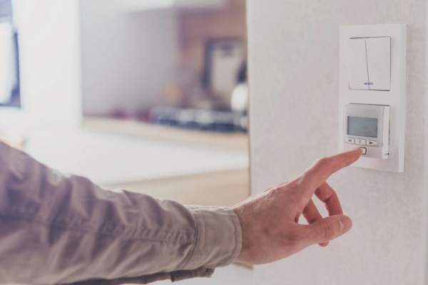 man's hand setting the temperature on programmable thermostat