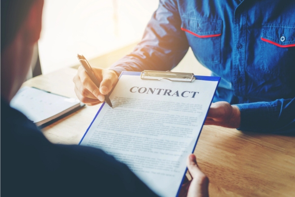 two men negotiating with a contract on a clipboard