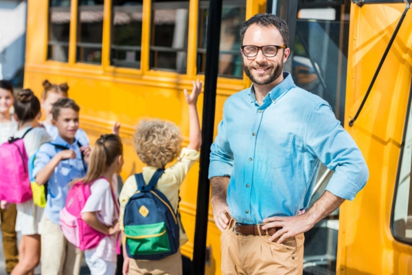 teacher and students by a school bus